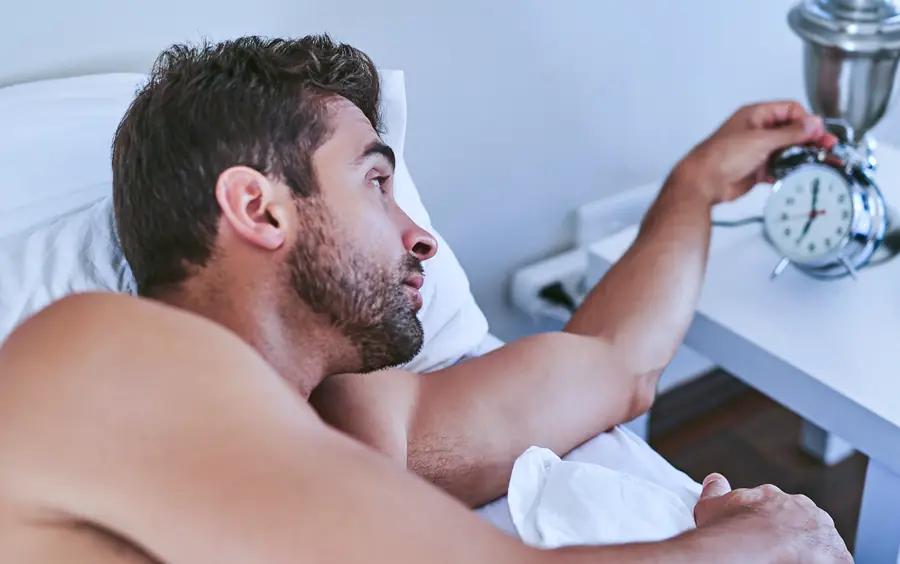 Homem na cama desligando o despertador
